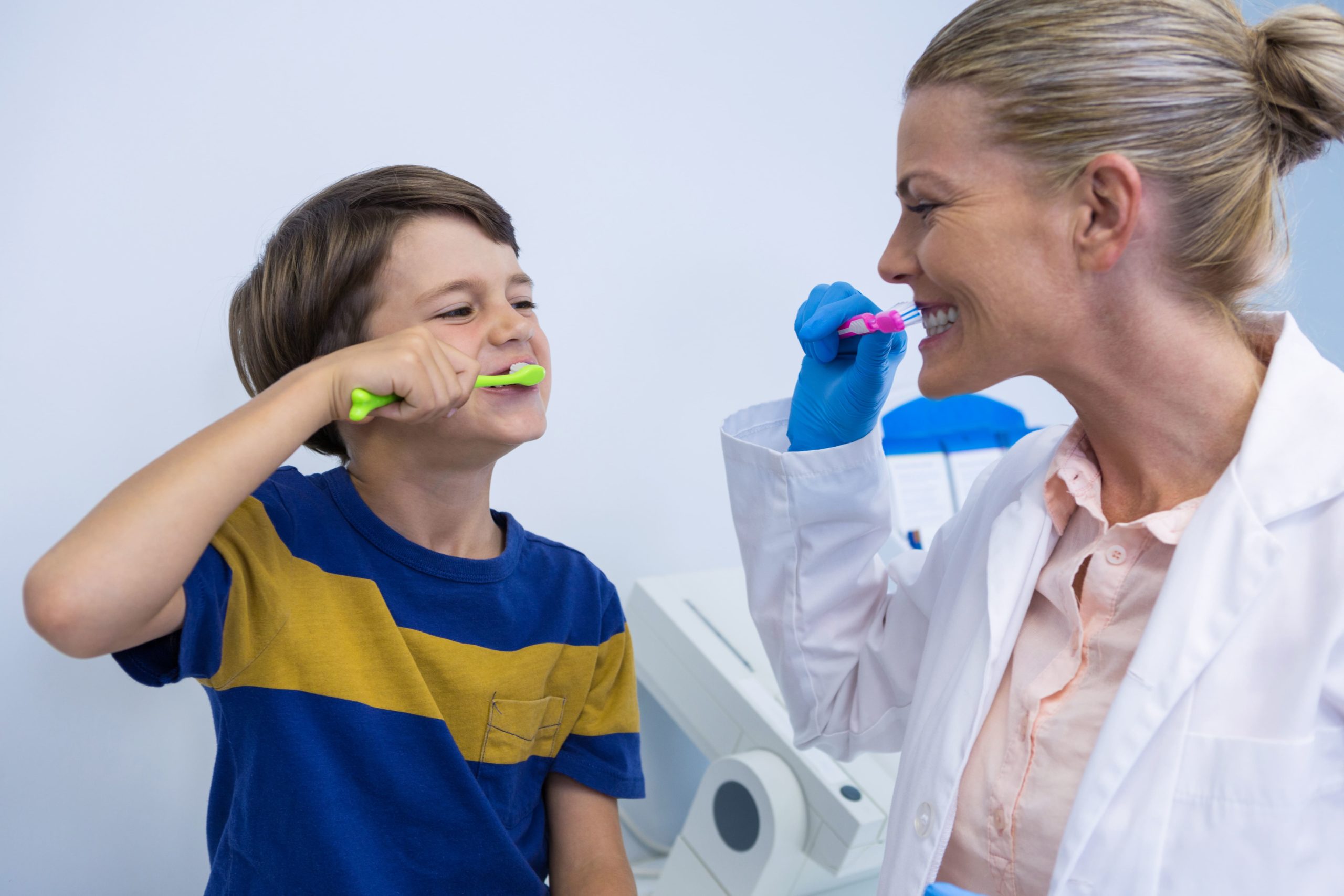 happy-dentist-and-boy-brushing-teeth-against-wall