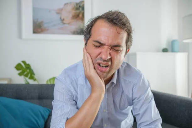 Hombre con dolor debido a Caries por rechinar los dientes