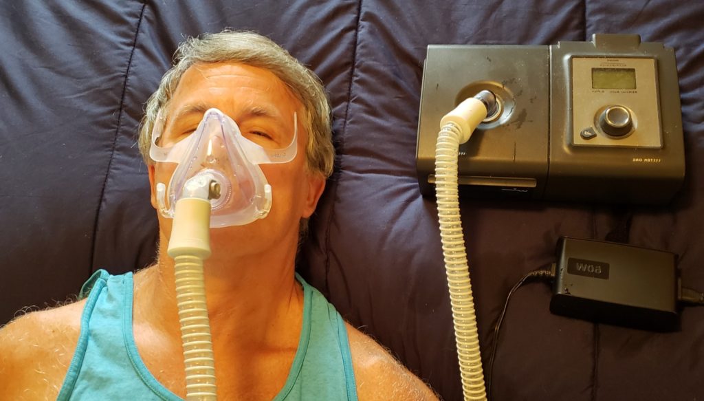 Snoring man is taking a nap with his breathing apparatus.