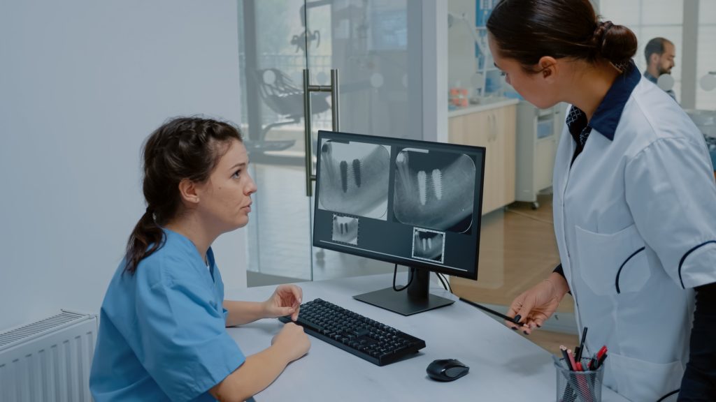 Stomatologist and nurse examining dental x ray scan