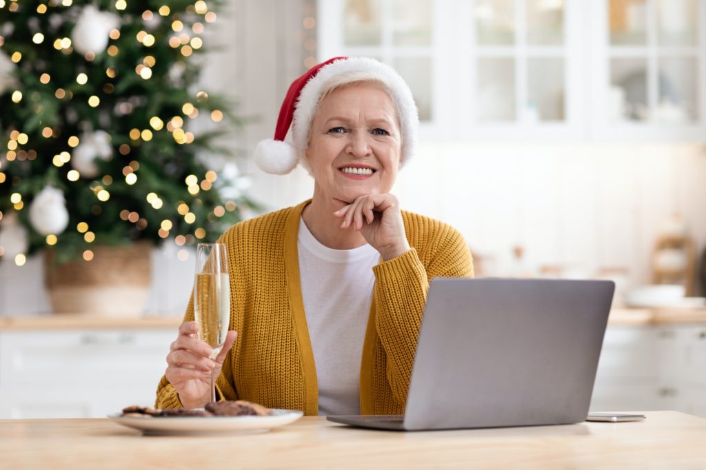 Beautiful granny in Santa hat sitting in front of laptop