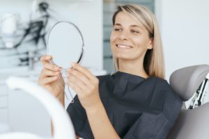 Patient looking to her smile in the mirror after treatment