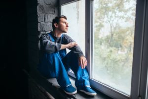Depressed man sitting on the window sill, psycho