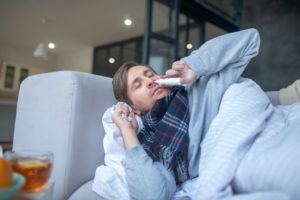 Sick man using nasal spray while having stuffy nose