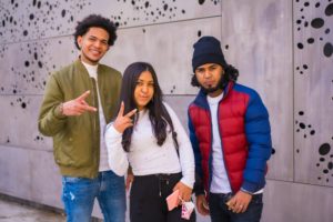 Urban style, three black Latino friends having fun in the street and talking to each other