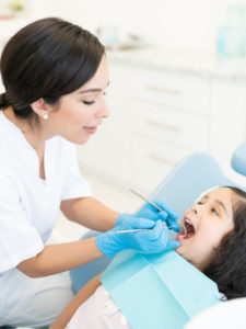 Dentist Checking Teeth Of Kid At Clinic