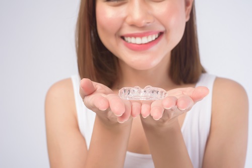 young-smiling-woman-holding-invisalign-braces