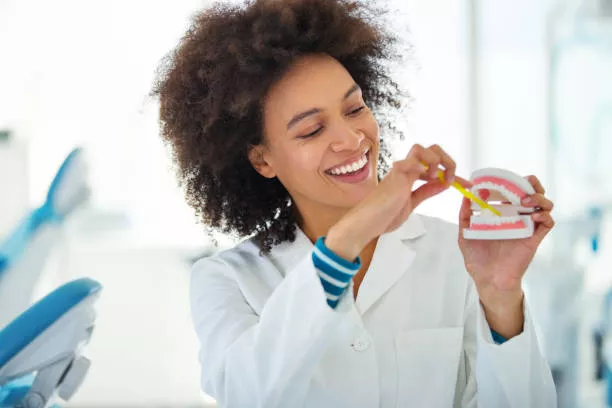 dentist holding a plastic denture and showing the correct way of brushing