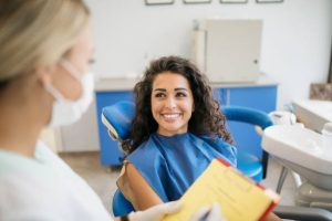 woman smiling and sitting in a dentist's office