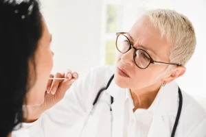 Enfermedades de la lengua. Médico revisa la lengua de una paciente.