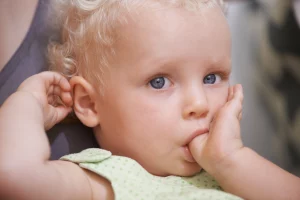 Niña chupando dedo. Causa de apiñamiento dental. Foto de una niña chupando dedo, la cual es una causa de tener los dientes torcidos o apiñamiento dental.