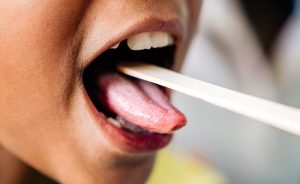 Pediatrician examining little girl's throat with tongue depressor