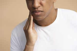 man-pressing-his-swollen-cheeks