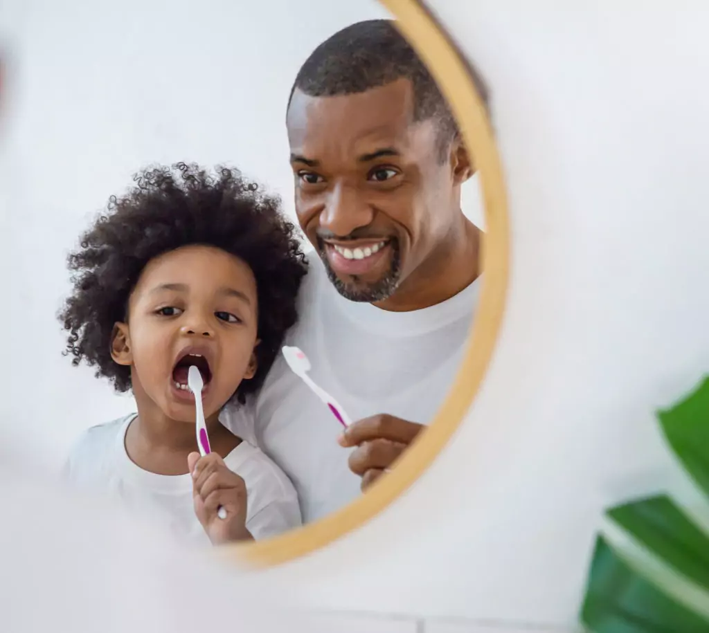 child brushing with his father