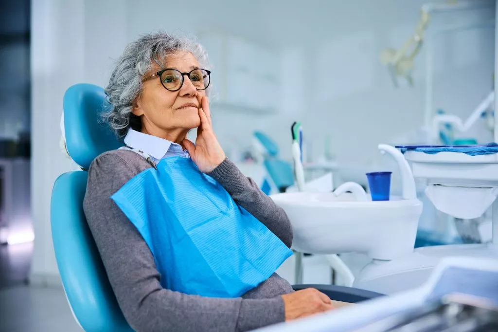 Senior woman with toothache at dentist's chair.