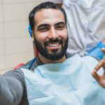 Blogging vlogging concept. Man taking selfie on smart phone while visiting orthodontist